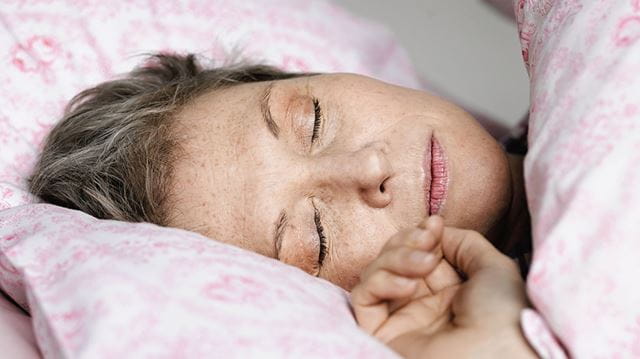 How to train yourself to sleep better; woman in pink bed